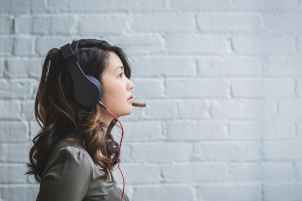 A woman listening to music on headphones. Credit: Canva