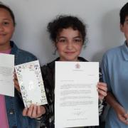 Yara Tadfi, Devon Wyer and Joseph Quail with their letters and cards from the King and Queen